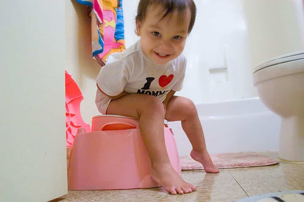 Asian toddler sitting on pink potty