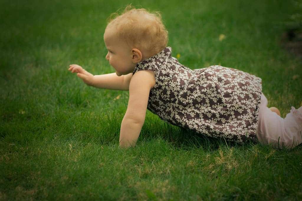 Nine month old toddler crawling in grass