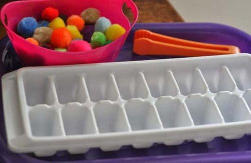 Sorting small pom-poms with tweezers helps strengthen little fingers.