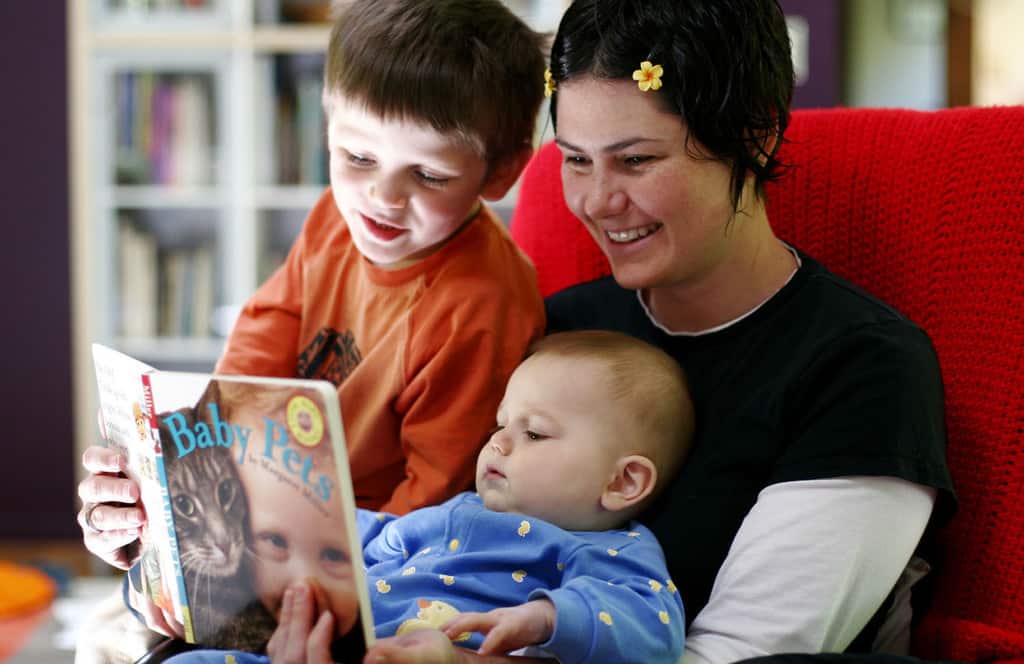 Mother reading to preschooler and infant