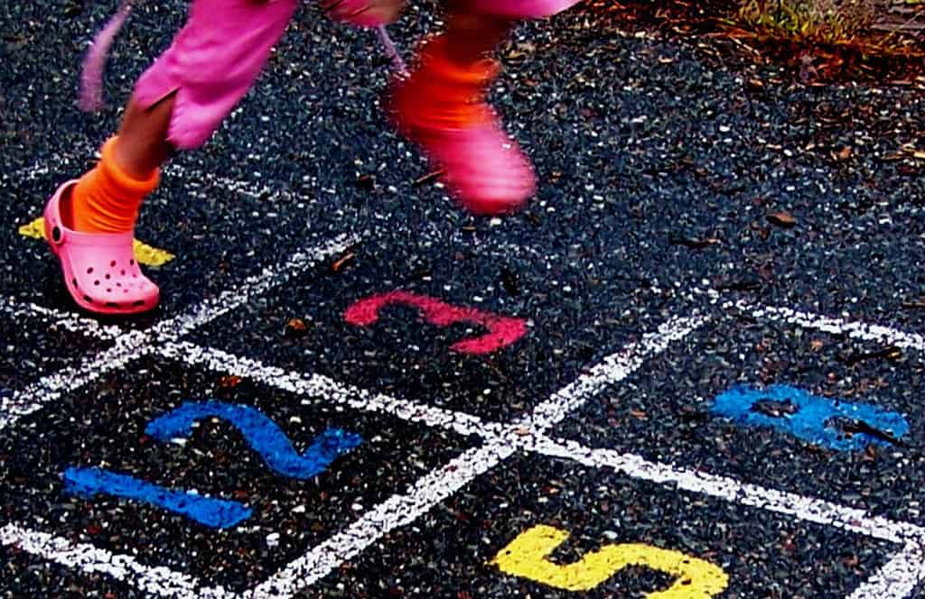 Girl running with pink shoes on hopscotch court