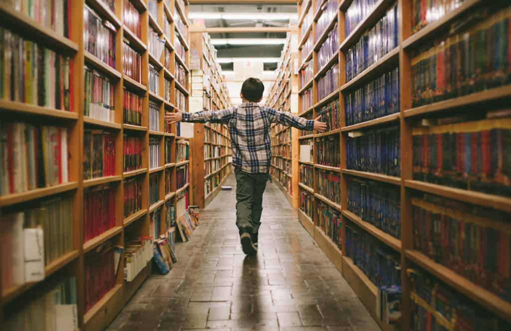 Boy walking through library of books