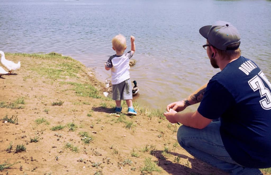 Toddler throwing bread to ducks