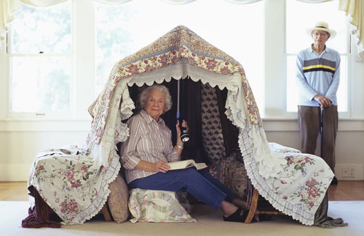 Grandmother in play tent reading with flashlight